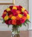 Arreglo floral MARIELLA con 36 rosas frescas en tonos rojo, amarillo, fucsia y naranja, presentado en un elegante jarrón de c