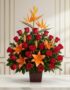 Arreglo floral 'Me Encantas' con lirios naranjas, rosas rojas y aves del paraíso, sobre una mesa de mármol en un entorno eleg