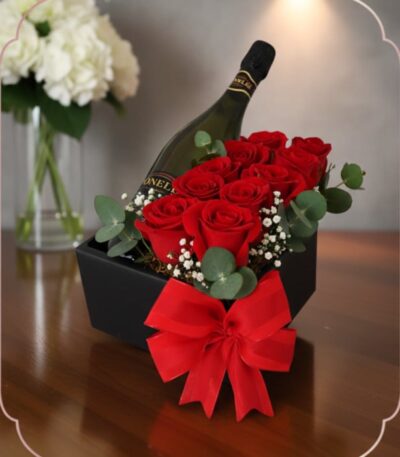 Arreglo floral NATALE con rosas rojas frescas, vino espumoso y lazo rojo en caja negra, ideal para regalo elegante.