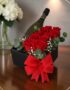 Arreglo floral NATALE con rosas rojas frescas, vino espumoso y lazo rojo en caja negra, ideal para regalo elegante.