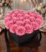 Arreglo Floral Perla con 24 rosas rosadas vibrantes en una caja negra en forma de corazón, sobre una mesa de madera pulida en