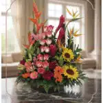 Arreglo floral PIA con rosas rosadas, girasoles, aves del paraíso y flores exóticas en un fondo elegante y luminoso.