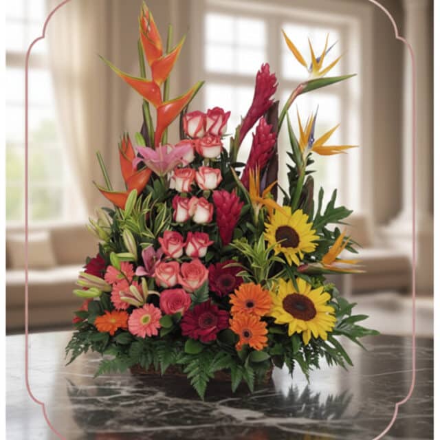 Arreglo floral PIA con rosas rosadas, girasoles, aves del paraíso y flores exóticas en un fondo elegante y luminoso.