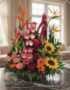 Arreglo floral PIA con rosas rosadas, girasoles, aves del paraíso y flores exóticas en un fondo elegante y luminoso.