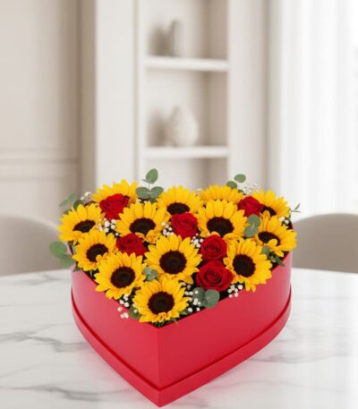 Arreglo floral RINA en forma de corazón con girasoles vibrantes y rosas rojas, ideal para expresar amor y alegría en cualquie