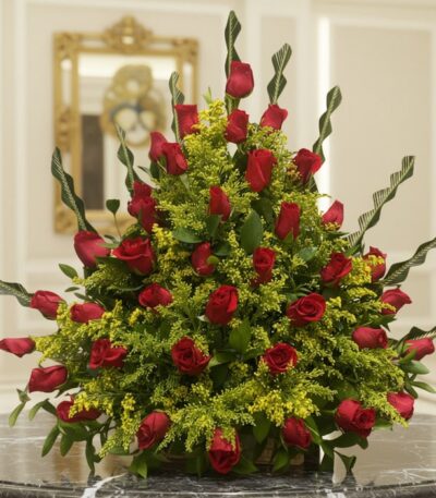 Arreglo floral premium con rosas rojas Cupido y follaje verde, sobre una mesa de mármol en un lobby de hotel boutique, ideal