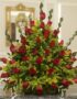 Arreglo floral premium con rosas rojas Cupido y follaje verde, sobre una mesa de mármol en un lobby de hotel boutique, ideal
