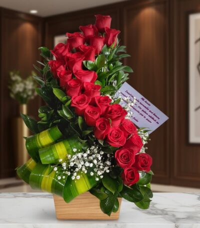 Arreglo floral premium con rosas rojas en espiral, follaje verde y flores blancas, sobre mármol en un entorno elegante.