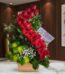 Arreglo floral premium con rosas rojas en espiral, follaje verde y flores blancas, sobre mármol en un entorno elegante.