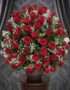 Impresionante arreglo floral de rosas rojas frescas y gypsophila en un jarrón gris sobre una mesa de madera, con un fondo ele