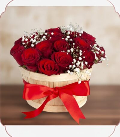 Arreglo floral 'Lidia' con 15 rosas rojas premium en un balde rústico de madera, adornado con un lazo rojo y follaje blanco,