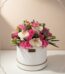 Arreglo floral TANIA con rosas rosadas vibrantes y orquídeas blancas delicadas en una caja redonda blanca con borde dorado, i