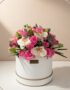 Arreglo floral TANIA con rosas rosadas vibrantes y orquídeas blancas delicadas en una caja redonda blanca con borde dorado, i