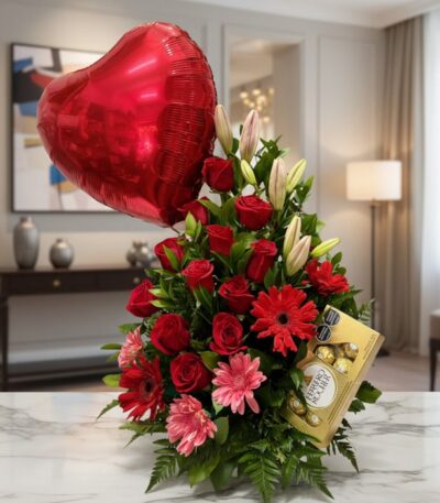 Arreglo floral 'Te Amo' con rosas rojas, lirios blancos, gerberas rosadas y rojas, follaje verde, un globo de corazón rojo y
