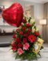 Arreglo floral 'Te Amo' con rosas rojas, lirios blancos, gerberas rosadas y rojas, follaje verde, un globo de corazón rojo y