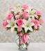 Arreglo floral vibrante con rosas rosadas, lirios blancos y claveles rosados en un jarrón de cristal con lazo rosa, ideal par