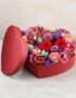 Arreglo floral ZITA en caja de corazón roja con rosas rojas, rosadas y flores mixtas, ideal para regalar en ocasiones especia