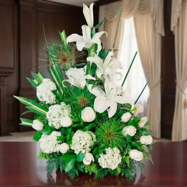 Arreglo fúnebre Adiós Para Siempre con lirios, hortensias y rosas blancas, en una sala de velación premium con luz natural y