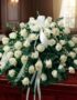 Arreglo fúnebre cubre caja Misericordia con rosas blancas frescas y follaje verde, presentado en una sala de velación premium