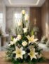Arreglo fúnebre 'Descanso Eterno' con lirios y rosas blancas, follaje verde, en sala de velación premium con luz natural suav