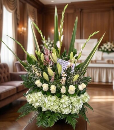 Arreglo floral fúnebre 'Eterno Descanso' con lirios, rosas blancas e hortensias, en una sala de velación premium con luz natu
