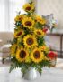 Arreglo floral premium con girasoles vibrantes y follaje verde, presentado en un jarrón blanco sobre una mesa de mármol en un