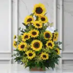 Arreglo floral de girasoles radiantes en un jarrón de madera, sobre una superficie de mármol, con un fondo elegante y luminos