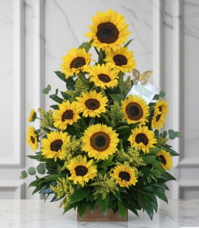 Arreglo floral de girasoles radiantes en un jarrón de madera, sobre una superficie de mármol, con un fondo elegante y luminos