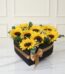 Arreglo floral con girasoles frescos y vibrantes en una elegante caja negra en forma de corazón, decorada con un lazo dorado,