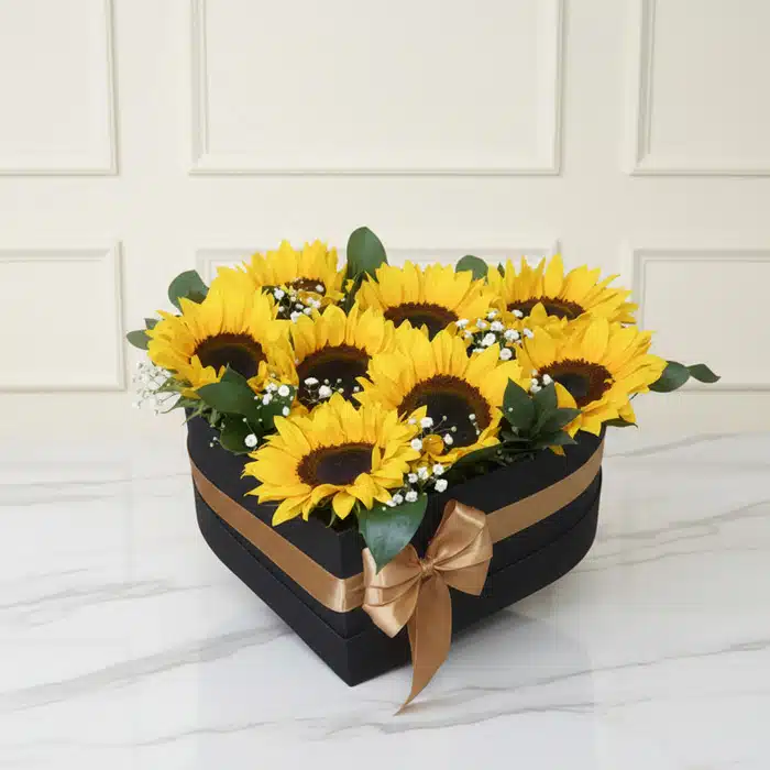 Arreglo Floral con Girasoles Soleil en Caja Corazón Negra Arreglo floral con girasoles frescos y vibrantes en una elegante caja negra en forma de corazón, decorada con un lazo dorado,
