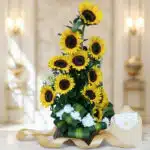 Arreglo floral alto con girasoles amarillos vibrantes y flores blancas, base de madera, cinta dorada, sobre elegante, sobre s