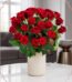 Arreglo floral Jianna con 25 rosas rojas frescas en un elegante jarrón blanco sobre mesa de mármol, fondo difuminado de sala