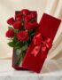 Caja premium de terciopelo rojo con 12 rosas rojas de exportación, frescas y con gotas de rocío, sobre una mesa de mármol bla