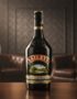 Botella de Baileys Original de 375ml con gotas de condensación, sobre una mesa de madera pulida, con un fondo elegante de cue