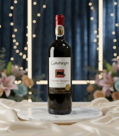 Botella de vino tinto Gato Negro Cabernet Sauvignon en un elegante estudio con arreglo floral y luces cálidas, ideal para eco