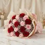 Bouquet ELETRA con 20 rosas rojas y rosadas, envuelto en papel coreano, sobre una superficie de mármol, ideal para regalar am