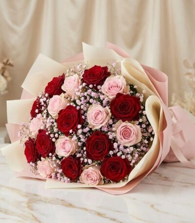 Bouquet ELETRA con 20 rosas rojas y rosadas, envuelto en papel coreano, sobre una superficie de mármol, ideal para regalar am