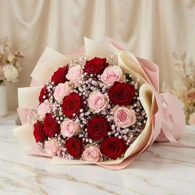 Bouquet ELETRA con 20 rosas rojas y rosadas, envuelto en papel coreano, sobre una superficie de mármol, ideal para regalar am