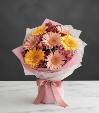 Bouquet de gerberas multicolor en tonos pastel (rosas y amarillas) con alstroemerias, envuelto en papel rosa y blanco, sobre