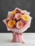 Bouquet de gerberas multicolor en tonos pastel (rosas y amarillas) con alstroemerias, envuelto en papel rosa y blanco, sobre