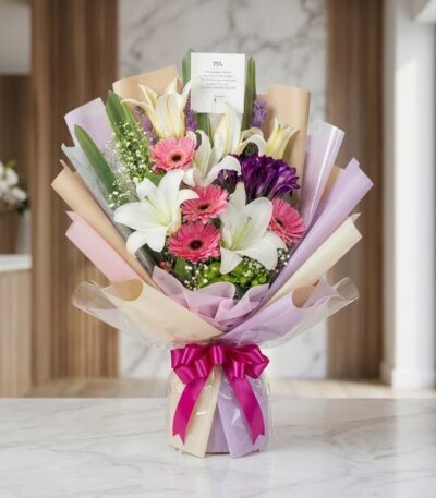 Bouquet de Flores GIA con gerberas rosadas, lirios blancos y flores moradas, envuelto en papel coreano elegante y lazo fucsia