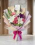 Bouquet de Flores GIA con gerberas rosadas, lirios blancos y flores moradas, envuelto en papel coreano elegante y lazo fucsia