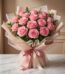 Bouquet Lionetta con 18 rosas rosadas frescas y abiertas, envuelto en papel coreano rosa y beige, sobre una mesa de mármol bl