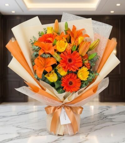 Bouquet LIRICA con lirios naranjas vibrantes, rosas amarillas abiertas y gerberas rojas, envuelto en papel coreano elegante s