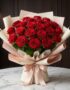 Bouquet MATILDE con 18 rosas rojas vibrantes, empaque coreano elegante en tonos crema y rosa, lazo de satén, sobre mesa de má