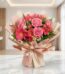 Bouquet ORLENA con rosas rosadas, gerberas fucsia y alstroemerias rojas, envuelto en papel coreano rosa claro sobre mármol bl