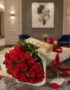 Elegante bouquet de rosas rojas frescas con bombones Ferrero Rocher sobre mesa de mármol en un lujoso recibidor.