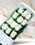 Caja de 12 rosas blancas frescas con moño blanco, presentadas elegantemente sobre un fondo de mármol claro, ideal para ecomme