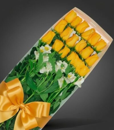 Caja de 18 rosas amarillas frescas con follaje verde y lazos dorados, ideal para regalar en cualquier ocasión especial.