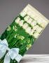 Caja de 18 rosas blancas frescas y vibrantes, con follaje verde y un lazo azul claro, sobre un fondo gris elegante. Ideal par